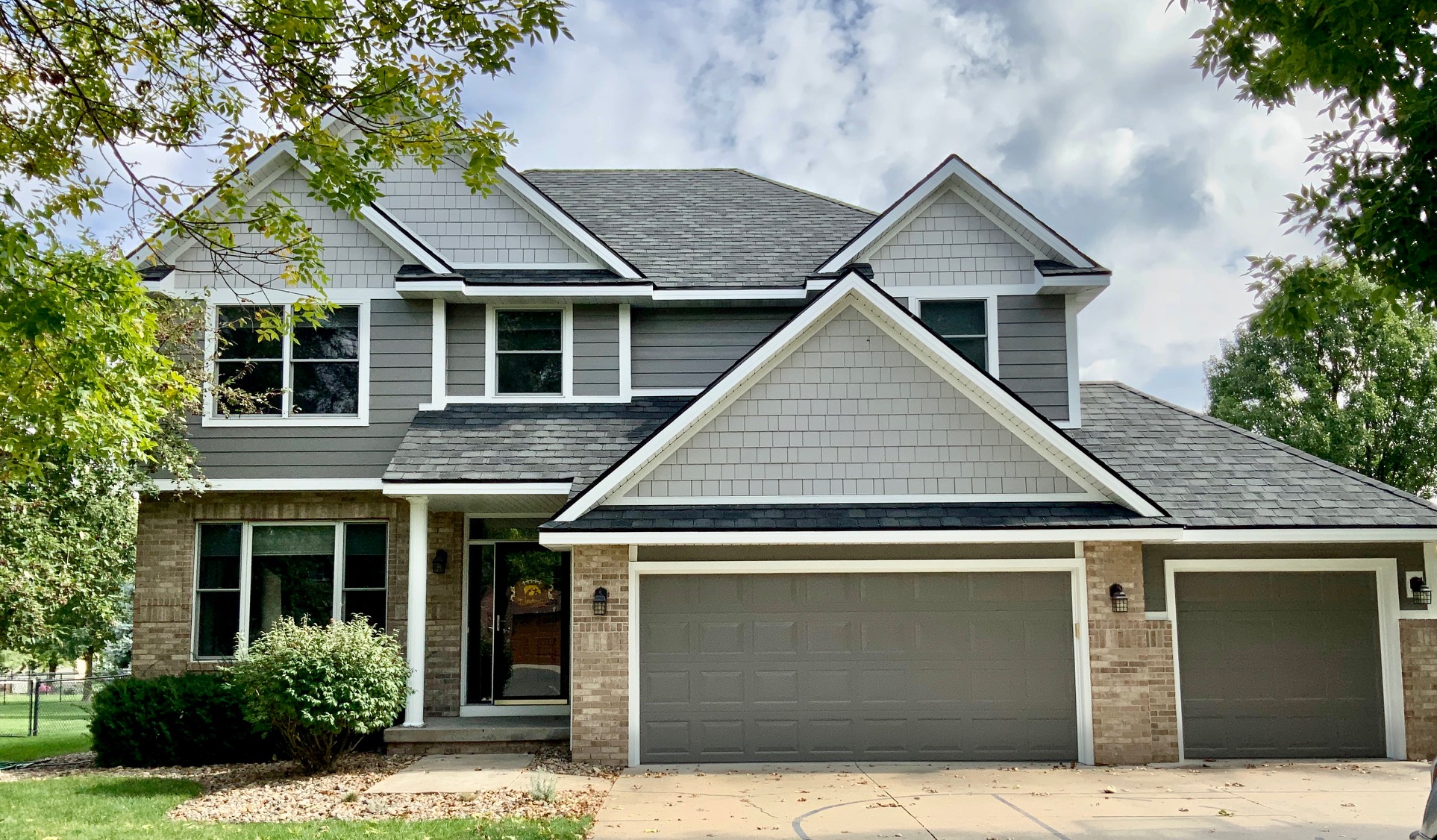 Front of house with grey siding and brick